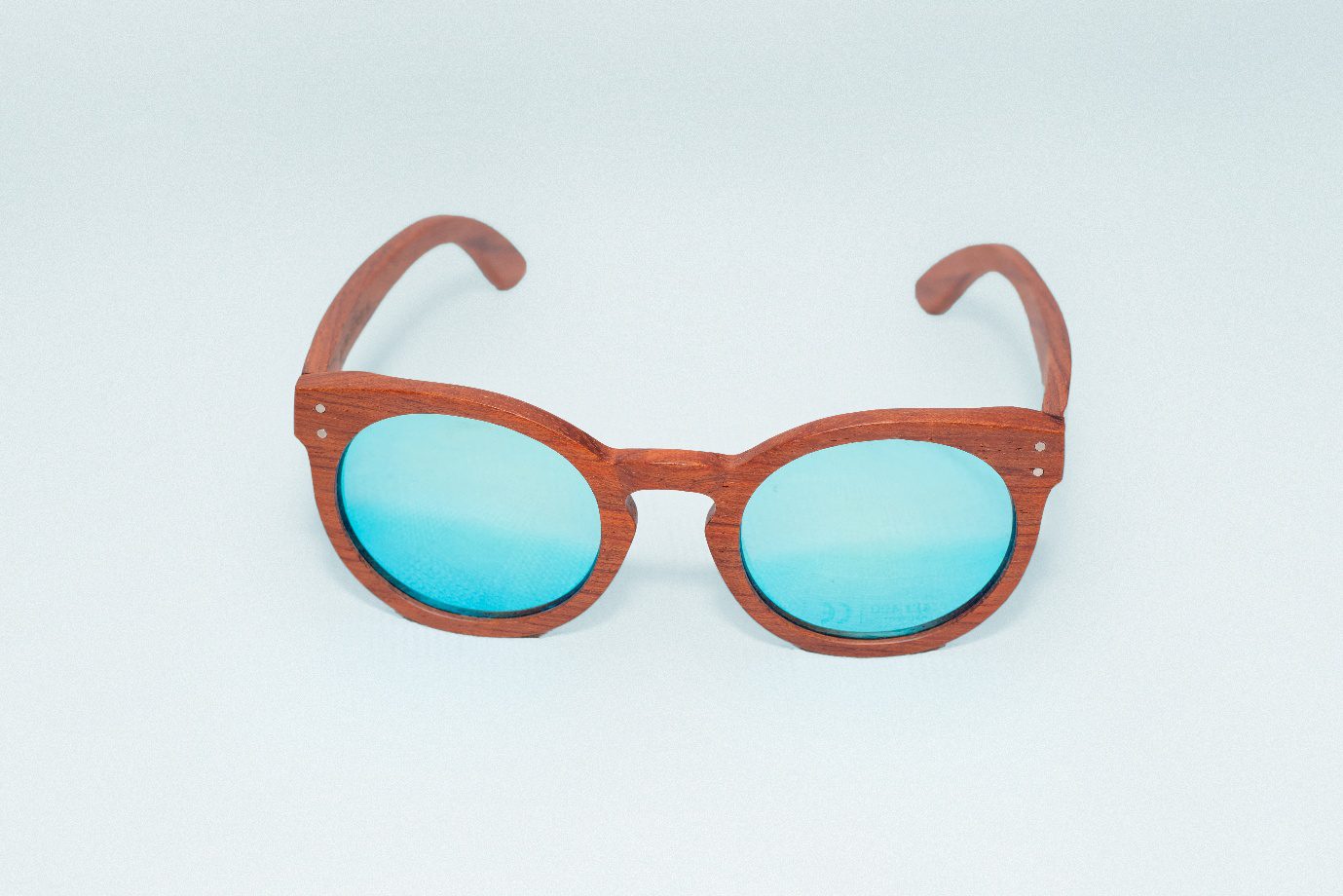 Kevazingo aurinkolasit (Sininen peililinssi) 1 Puukehyksiset käsintehdyt aurinkolasit sinisillä linsseillä. Suunniteltu Suomessa planeettaa kunnioittaen. Kestävästi valmistettu afrikkalaisista kierrätysmateriaaleista. Handcrafted wooden framed sunglasses with blue lenses. Designed in Finland with respect for the planet. Sustainably made from recycled African materials.