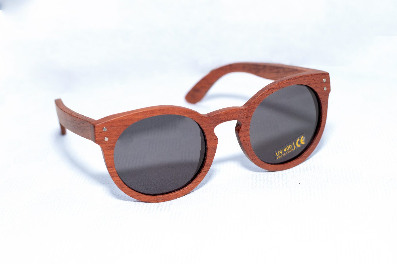 Kevazingo aurinkolasit (Harmaa linssi) 1 Kevazingo. Puukehyksiset käsintehdyt aurinkolasit harmailla UV400-linsseillä. Suunniteltu Suomessa planeettaa kunnioittaen. Kestävästi valmistettu afrikkalaisista kierrätysmateriaaleista. Handcrafted wooden framed sunglasses with grey UV400 lenses. Designed in Finland with respect for the planet. Sustainably made from recycled African materials.