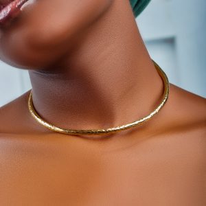 Afrikkalaistyylinen ohut, teksturoitu, vasaroitu käsityönä tehty messinkinen kaulakoru mallin kaulassa. Tribal thin textured, hammered brass choker necklace worn on a model's neck. CIMAX Design